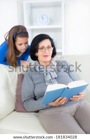 Grandmother and little girl reading a book happy together at home