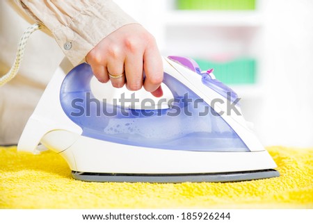 Close-up Of Woman\'s Hand Ironing Clothes On Ironing Board