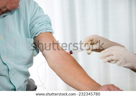 Nurse with syringe is taking blood for test at the doctor office