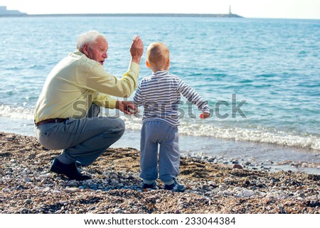 Grandfather and grandson throwing stones into the sea
