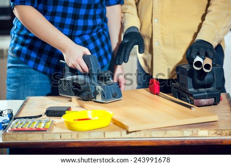 Home improvement - handy woman sanding wooden floor in workshop, handy man assisting, selective focus