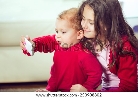 Happy brother and sister take pictures with telephone