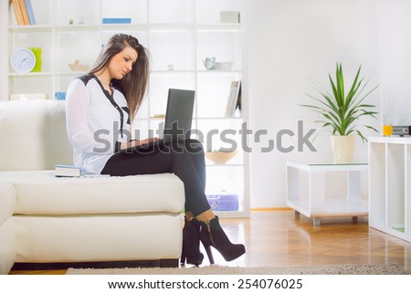 Young woman browsing internet on laptop computer at home on sofa