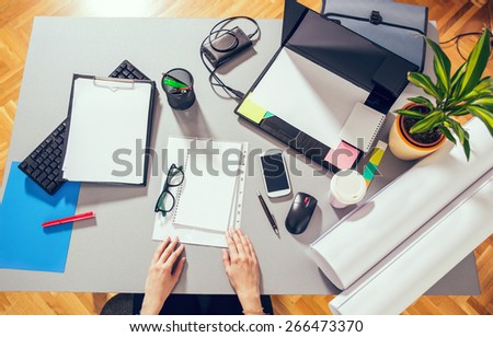 Mix of office supplies and gadgets on a wooden desk background. View from above. Selective focus