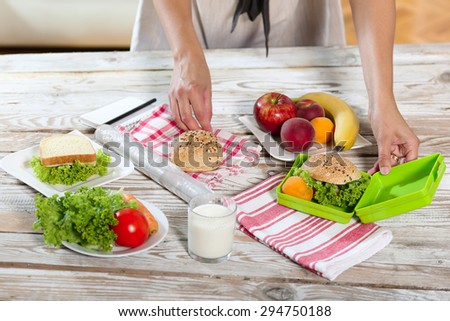 Mother preparing healthy and tasty lunch box for child