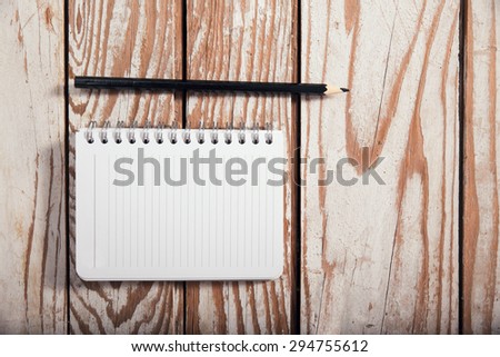 Blank note book paper and pencil on wooden background
