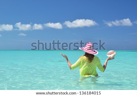 Girl with a shell in her hand in the turquoise Atlantic water. Exuma, Bahamas