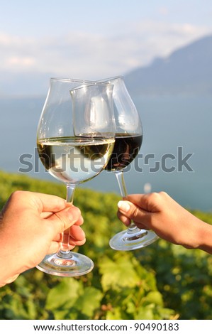 Two hands holding wineglasses against vineyards in Lavaux region, Switzerland