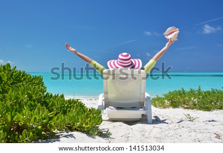 Girl with a shell on the sunbed looking to the ocean. Exuma, Bahamas