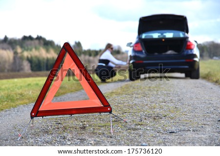 Girl, broken car and warning triangle