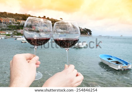 Two wineglasses in the hands against the harbour of Portvenere, Italy