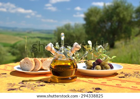 Olive oil and olives on the wooden table against Tuscan landscape. Italy
