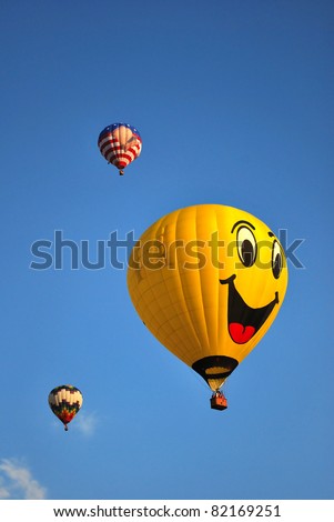 Smiley face hot air balloon against clear blue sky