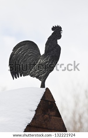 Metal rooster on the roof of a wooden