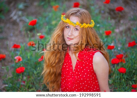 Pretty red-haired girl with curls  in nature  in red dress