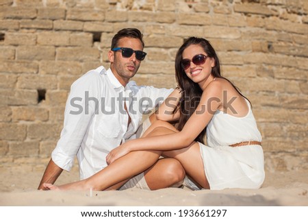 Couple on beach. Young happy man and woman sea shore smiling romantic looking each other, summer ocean vacation holiday blue sky