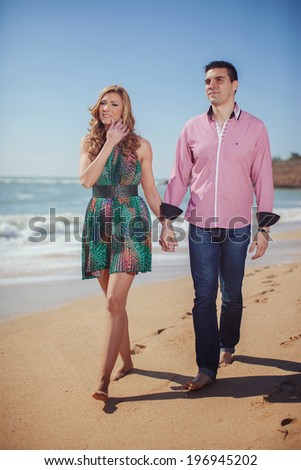 Attractive Young Couple on the Beach. Vacation couple walking on beach together in love holding around each other. Happy interracial young couple
