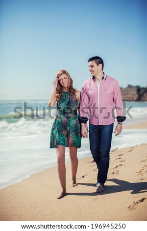 Attractive Young Couple on the Beach. Vacation couple walking on beach together in love holding around each other. Happy interracial young couple