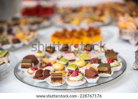 Rows of tasty looking desserts in beautiful arrangements. Mini desserts on catering buffet white tablecloth