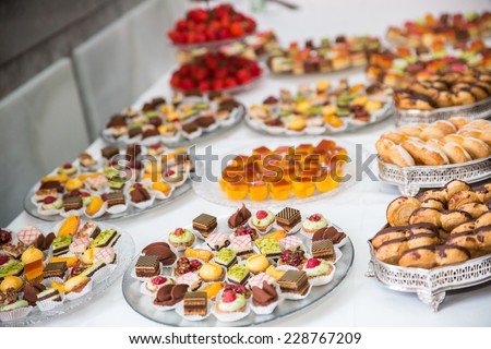 Rows of tasty looking desserts in beautiful arrangements. Mini desserts on catering buffet white tablecloth. Sweets on banquet table - picture taken during catering event
