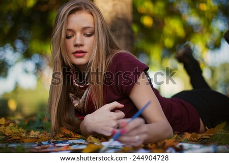 Young woman drawing  in beautiful autumn park, concept autumn