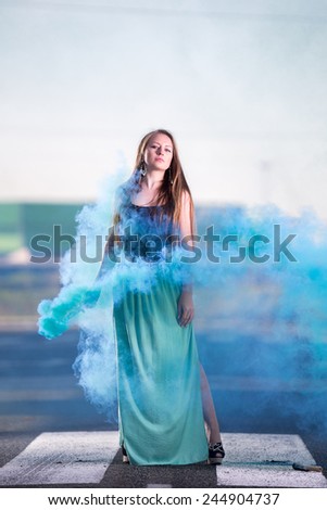 Portrait of a  young woman with blue cloudy smoke