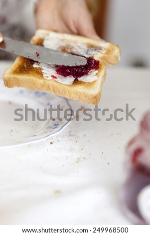 woman hand rubs butter on piece of  bread, with selective soft focus