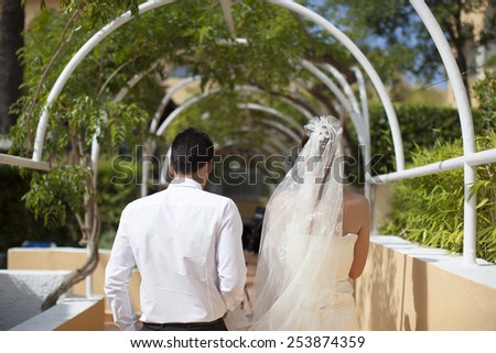 Bride and groom walking away in summer park outdoors