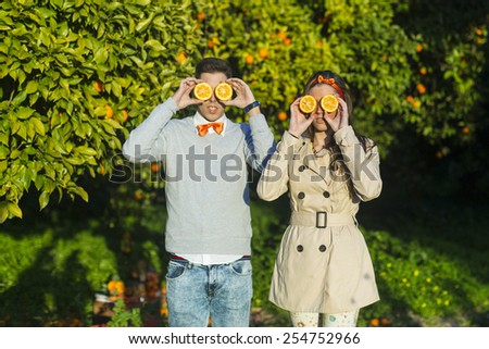 young couple holding oranges over eyes.