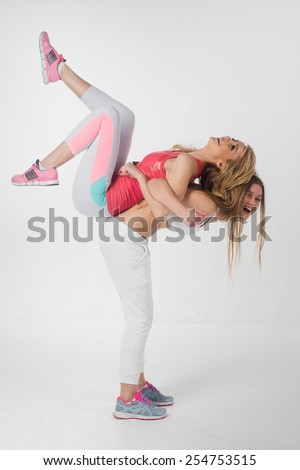 Two attractive athletic girl wearing sportswear having fun over white background