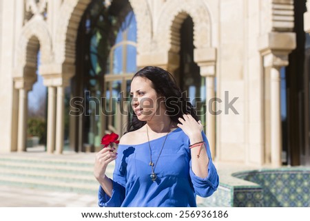 Portrait of Spanish young adult woman with big red rose