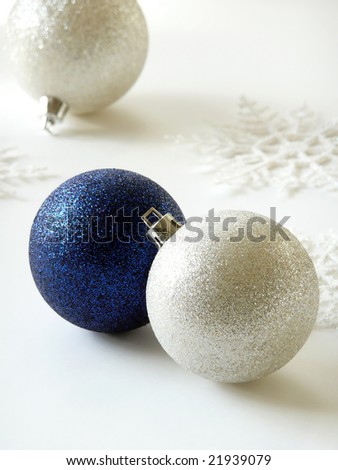 Glittery blue and silver Christmas ornaments with a white background and snowflakes.