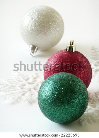 Red, green and silver Christmas ornaments on white background with snowflake decorations.