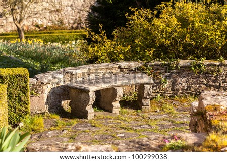 Garden seat on stone patio in spring garden