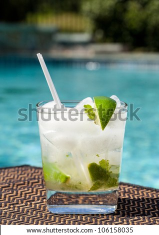 Glass of ice cold majito in glass by side of swimming pool