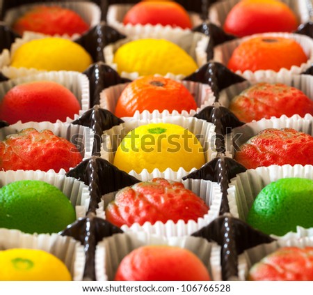 Fruit shaped candies in macro image of marzipan sweets in paper wrappings