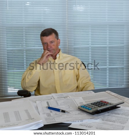 Senior caucasian man weary from preparing tax form 1040 for tax year 2012  with calculator