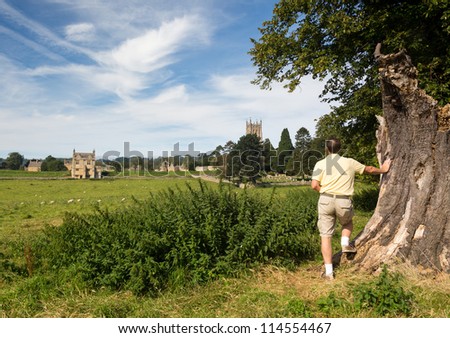 Man looking at St James Church seen across meadow in old Cotswold town of Chipping Campden