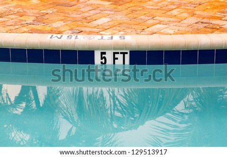 Sign showing 5 ft depth on edge of blue swimming pool with no diving