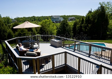 Middle aged lady relaxing on a deck by a swimming pool