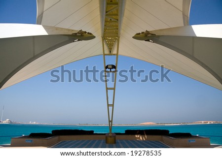 Modern sail like construction providing shade and framing a view of gulf and distant sand dunes