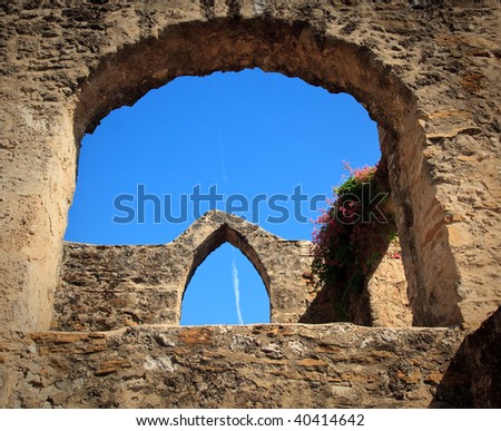 View of an old arch in San Juan Mission in Texas with modern jet trail in sky