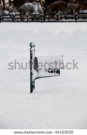 Green mailbox buried in deep snow by covered road
