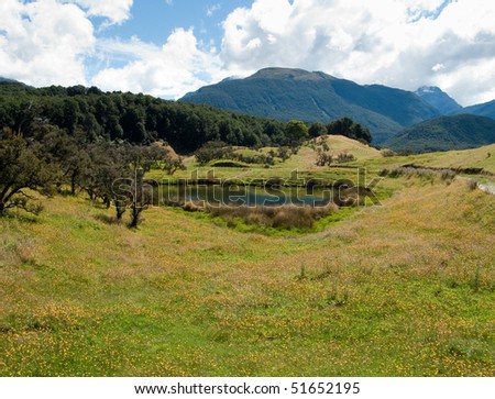 Rolling countryside valley in New Zealand with lake and mountains