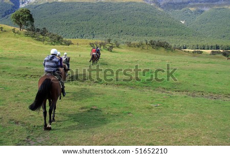 Row of horse riders in line going across a field