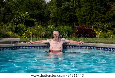 Man in his fifties relaxing in a pool in a backyard garden