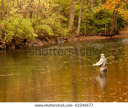 Angler fishing in a deep river in fall with the leaves changing colors