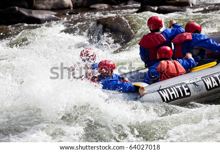 Group of adventurers in an inflatable dinghy in the white water of a fast moving river