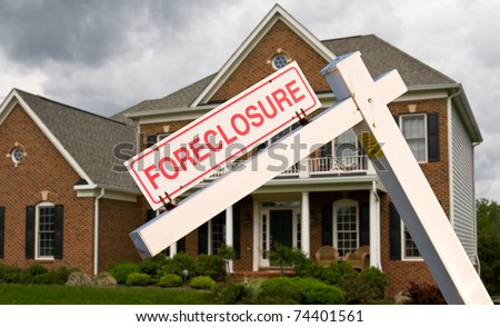 Leaning foreclosure sign in front of a modern single family home on a cloudy cold day