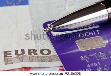 Macro of debit card and pen on top of euro note to illustrate currency crisis in Europe